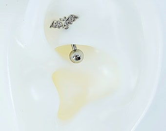 May include: Silver bat cartilage piercing with a silver ball on the end.