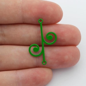 Può includere: Due ciondoli in metallo verde brillante con un design a volute decorativo. Ogni ciondolo ha una barra verticale con un anello in alto e in basso e un ricciolo stilizzato sul lato. I ciondoli sono mostrati su sfondo bianco.
