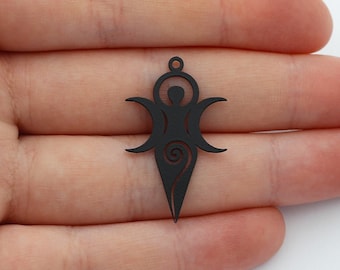 May include: A matte black metal pendant featuring a stylized figure with outstretched arms flanked by two crescent moons, topped with a small circular loop for hanging, and finished with a pointed base containing a spiral cutout design.