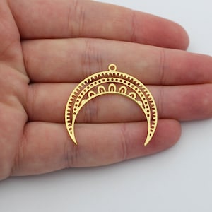May include: Two gold-colored metal crescent moon charms featuring intricate cut-out patterns, including a row of small dots and arched shapes along the inner curve, with a small circular loop at the top center for attachment purposes.