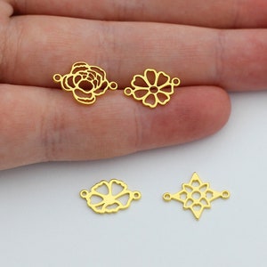 May include: Three gold-toned metal charms in the shape of flowers. The charms have openwork designs and are perfect for jewelry making.