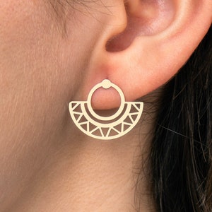 Peut inclure: Boucles d'oreilles géométriques dorées avec un design circulaire. Les boucles d'oreilles sont portées à l'oreille d'une personne.