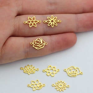 May include: A collection of gold-toned metal flower charms with openwork designs. The charms are arranged on a hand, showcasing their delicate details.