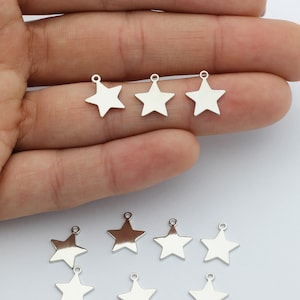 May include: A set of ten silver star-shaped charms with a hole at the top for attaching to jewelry or other crafts.