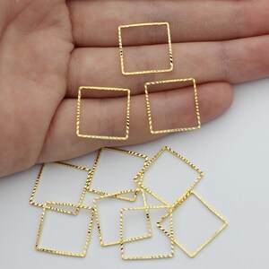 Può includere: Una collezione di piccole cornici quadrate color oro con una superficie testurizzata a taglio diamante. Questi componenti quadrati a centro aperto sono sottili e metallici, caratterizzati da un motivo ripetitivo su ogni lato.