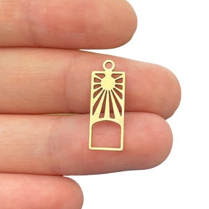 May include: Gold-toned metal charm with a sunburst design. The charm has a rectangular shape with a smaller rectangular cutout in the center. The charm has a loop at the top for attaching to a necklace or bracelet.