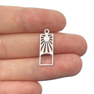 May include: Silver charm with a sunburst design inside a rectangular frame. The charm has a hole at the top for attaching to a necklace or bracelet.