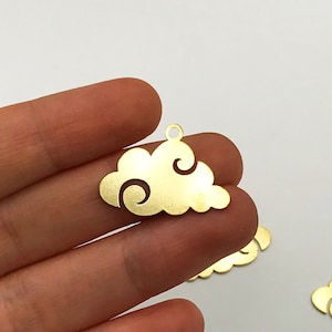 May include: Gold-colored cloud-shaped charms with a small hole at the top for stringing. The charms have a cutout design and are likely for jewelry making or other crafts. The image shows several charms.