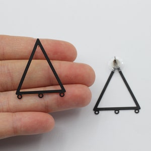 Puede incluir: Un par de bases para pendientes triangulares negros con tres anillos de salto en la parte inferior de cada triángulo.
