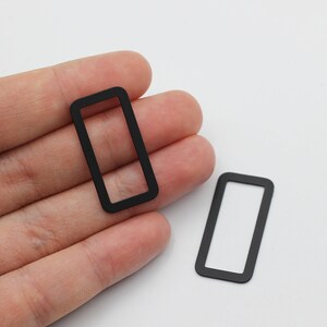 May include: Two black rectangular frames with rounded corners. The frames are made of a thin, flexible material.