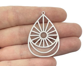May include: A silver-toned metal pendant in a teardrop shape featuring a central circular cutout with radiating spokes and two curved lines at the base. The piece includes a small loop at the top for attachment, showcasing a flat, cut-out design.