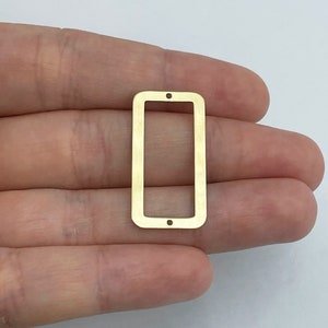 May include: Gold-toned metal rectangle frame with two holes at the top. The frame is about 1 inch wide and 2 inches long.