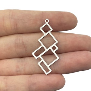May include: A silver-toned metal pendant featuring a geometric arrangement of interconnected open squares and rectangles. The design consists of multiple hollow shapes linked together in a vertical, cascading pattern with a small loop at the top.