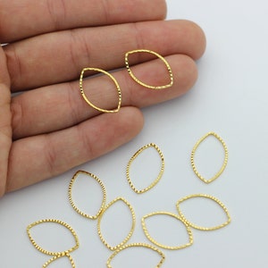 May include: A collection of gold-toned metal oval-shaped jump rings. The rings have a textured surface and are ideal for jewelry making.