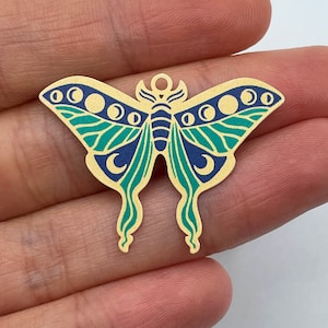 Puede incluir: Encanto de metal dorado en forma de mariposa verde y azul con fases lunares en las alas.