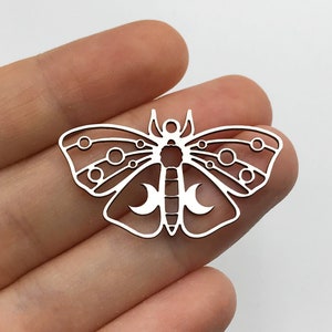 Puede incluir: Encanto de metal plateado en forma de mariposa con recortes de luna y círculo.