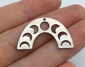 May include: A silver-toned metal charm shaped like an arch, featuring a series of cut-out moon phases including crescents and a full circle. The piece has a small hole at the top center for attachment, with a brushed finish on the flat surface.
