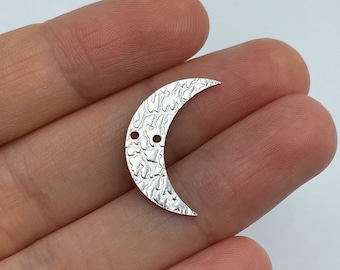 May include: Silver crescent moon charm with a hammered texture and two holes for attaching jewelry findings.