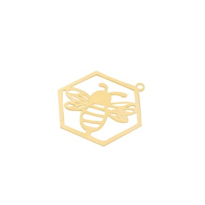 May include: Gold-toned metal charm shaped like a hexagon with a bee cutout inside. The bee has striped wings and a body.