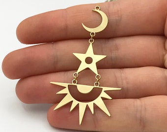 May include: Gold-toned dangle earrings featuring a crescent moon, star, and sun design. The sun has a circular center and radiating points.