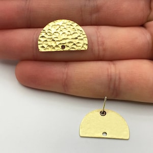 May include: Two gold-toned metal half-circle earring blanks with a hammered texture. The earring blanks have a hole in the centre for attaching earring posts.