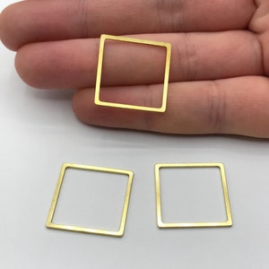 Op de afbeelding: Drie goudkleurige vierkante metalen sieradenonderdelen. De onderdelen zijn open omlijst, met een vierkante vorm. De onderdelen worden gepresenteerd op een wit oppervlak.