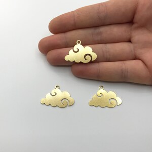 May include: Three gold-colored cloud charms with a swirling design. Each charm has a small loop at the top for attaching to jewelry or other crafts. The charms are displayed against a white background.