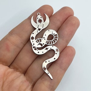 以下が含まれることがあります： 三日月と星がくり抜かれた蛇の形をした銀色の金属製チャーム。蛇は尾を口に入れて丸まっている。