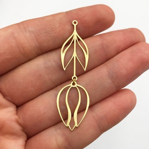 May include: Gold-toned metal pendant featuring a delicate leaf design with a dangling tulip-shaped charm. The pendant is designed for jewelry making and crafting.