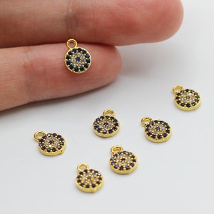 Könnte beinhalten: Goldfarbene böse Augen-Anhänger mit schwarzen und weißen Kristall-Akzenten. Die Anhänger haben eine Öse oben zum Anbringen an Schmuck oder andere Bastelarbeiten.