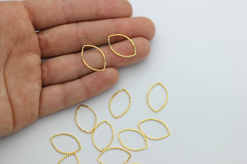 May include: A collection of gold-toned metal oval-shaped jump rings. The rings have a textured surface and are ideal for jewelry making.