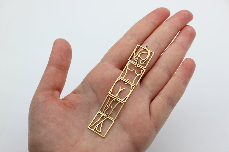 May include: Gold-toned metal pendant featuring a stylized female figure in four connected squares.