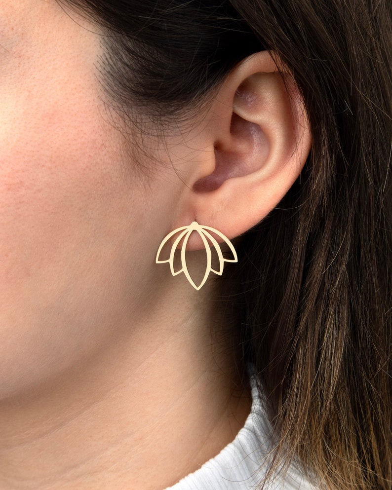 May include: A gold-toned stud earring featuring a symmetrical, open-work design that resembles a stylized lotus flower or a fan shape with five distinct, pointed petals. The piece has a smooth, polished finish and a clean, geometric aesthetic.