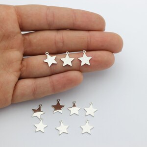 May include: Eight silver star-shaped charms with a loop at the top. The charms are arranged in two rows on a white surface.