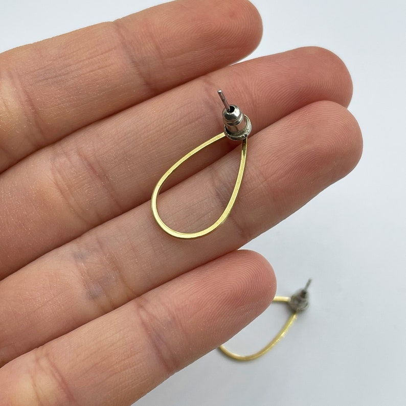 May include: A pair of gold teardrop shaped earrings with a silver post.