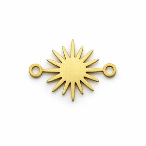 May include: A gold-toned metal jewelry connector featuring a central sunburst design with multiple radiating rays. The component includes a small circular loop on each side, extending horizontally from the sunburst shape for attachment purposes.