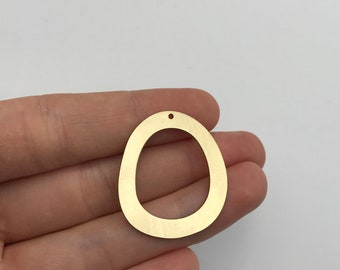 May include: A gold-toned metal pendant with an irregular, organic, egg-like shape and a smooth, brushed finish. The pendant features a single small circular hole at the top center for attachment, showcasing a flat, open-center design.