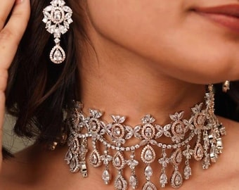 May include: A sparkling silver and clear crystal necklace and earring set. The necklace is a choker style with multiple layers of crystals and teardrop pendants. The earrings are a matching chandelier design with a teardrop crystal.