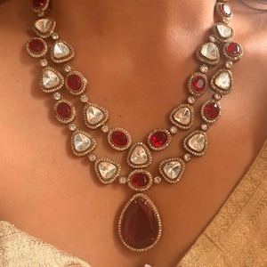 Peut inclure: Un collier en or à deux rangs avec des pierres précieuses rouges et blanches. Le collier présente un grand pendentif en forme de larme en pierre précieuse rouge.