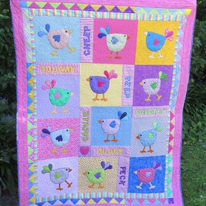 May include: A pink, yellow, blue, and green patchwork quilt with a variety of colorful birds and the words "Cheep", "Squawk", "Peep", "Scritch", "Cackle", "Cluck", "Peck" written on it.
