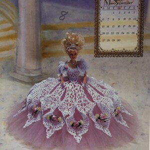 May include: A doll in a lavender and white crocheted gown with a pink tulle skirt. The doll has blonde hair and is wearing a pearl necklace and a tiara. The image includes a calendar for September 1998 and the text "An Annie Potter Original."
