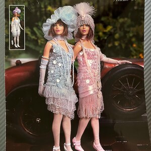 May include: A Paradise Publications Crochet Collector Costume Volume 90 pattern booklet titled 1925 Jeweled Flapper Girls. The cover features two dolls wearing beaded dresses, hats, and gloves, with text indicating the pattern includes 3 beaded dresses, hats, purses, and fox stoles.
