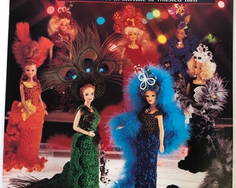 May include: A crochet pattern book featuring seven doll costumes. The cover shows five dolls wearing elaborate crocheted gowns with feathers and sequins. The book title is "Fashion Doll Showstoppers" and the subtitle is "7 Costumes in Chenille or Worsted Yarn". The book is by Giselle Exclusive Designs.