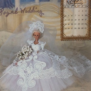 May include: A Barbie doll in a white wedding dress with a long train and veil. The dress features intricate lace detailing and a full skirt. The doll holds a bouquet of white flowers. The background includes the text "Royal Wedding" and a calendar for January 1998.