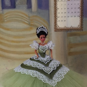 May include: A doll wearing a green and white crocheted gown with a tulle skirt, a tiara, and a necklace. A calendar for June 1998 is in the background. The text "An Annie Potter Original" is at the bottom.