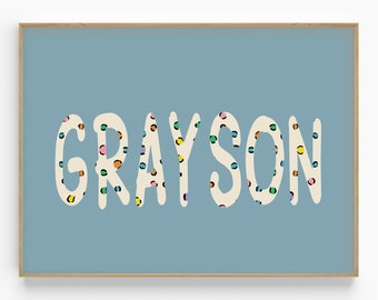 May include: A light blue background with the name "GRAYSON" in white letters with a colourful polka dot pattern.