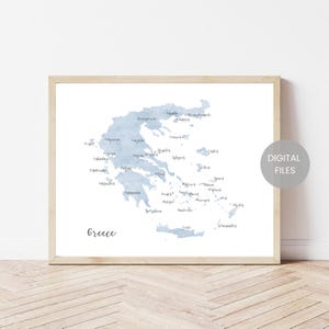 Peut inclure: Une carte aquarelle encadrée de la Grèce dans des tons bleus. La carte comprend les noms des villes et villages dans une police manuscrite. Les mots "Digital Files" sont dans un cercle blanc sur le côté droit.