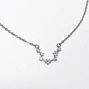 May include: A silver necklace with a constellation pendant featuring small clear cubic zirconia stones.