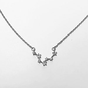 Op de afbeelding: Een zilveren ketting met een sterrenbeeld hanger met kleine, heldere zirkonia stenen.