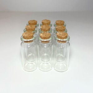 Peut inclure: Douze bouteilles en verre transparent avec des bouchons en li&egrave;ge. Les bouteilles sont dispos&eacute;es en quatre rang&eacute;es de trois bouteilles chacune.